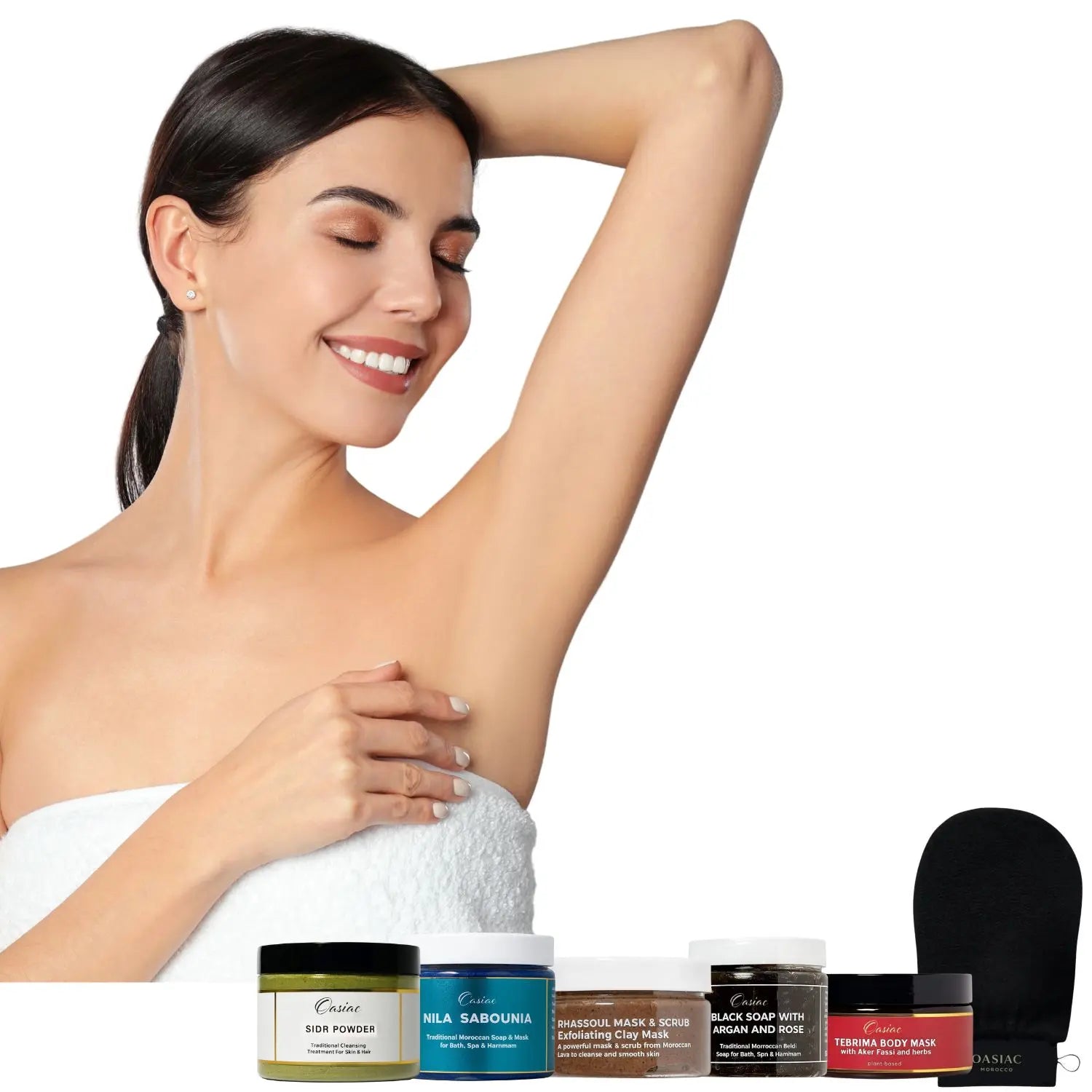 Woman with a towel around her shoulders next to various skincare products on a white background
